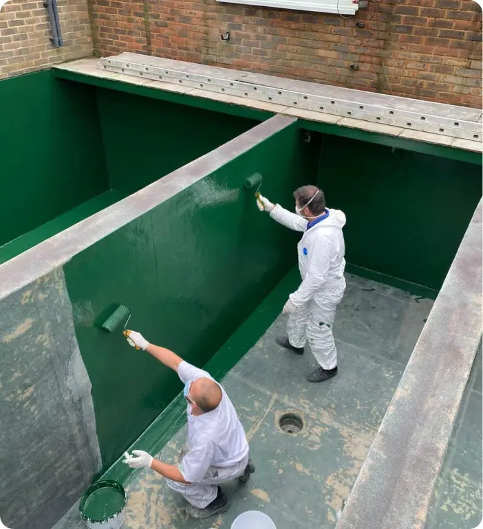 a couple of men painting a green wall