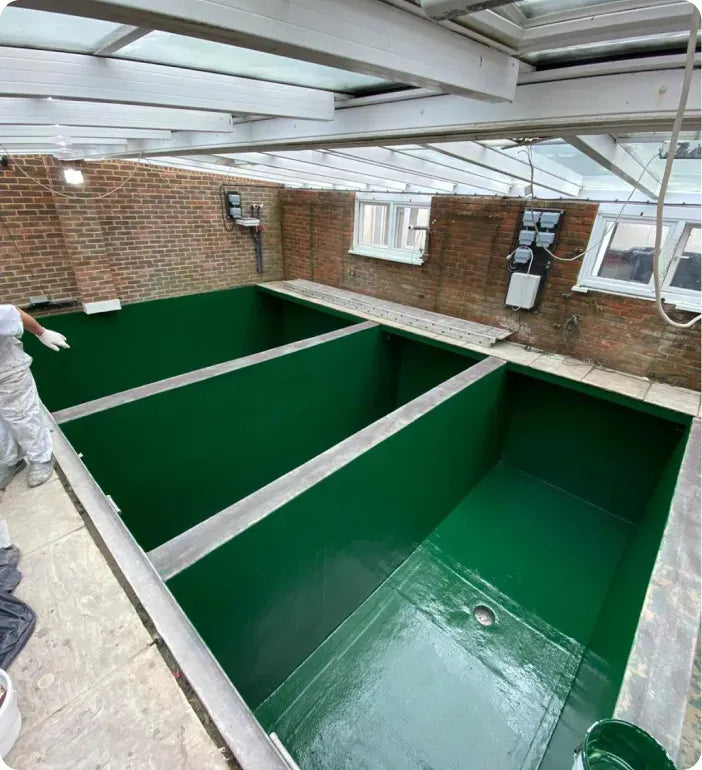 a man is painting a green pool in a building