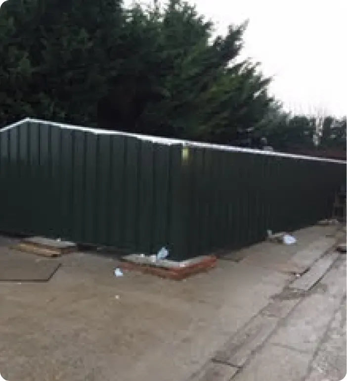 a green metal fence sitting on the side of a road