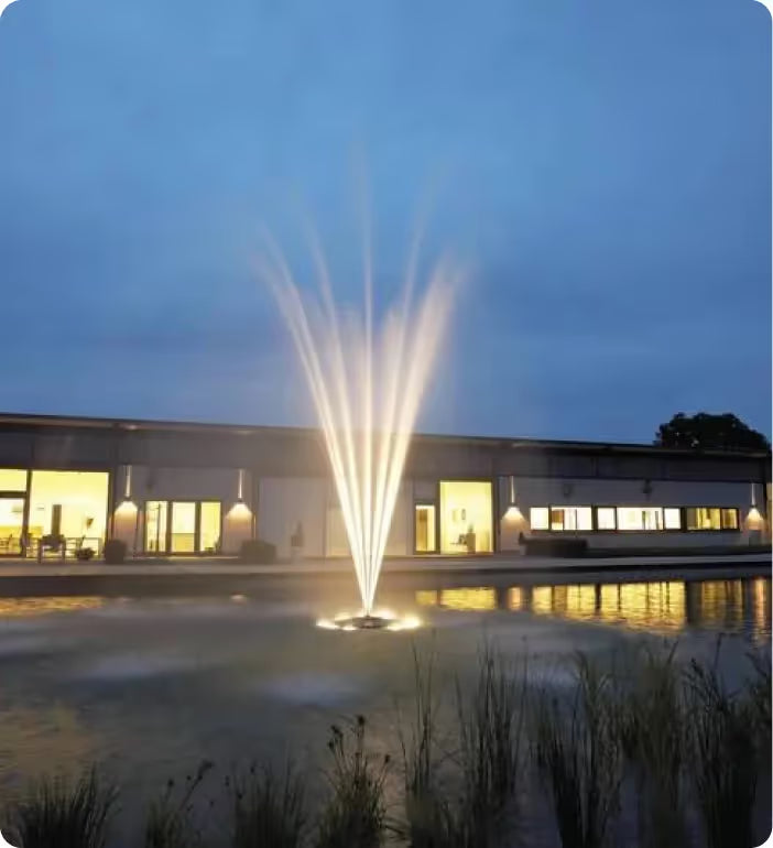 a large fountain in front of a building at night