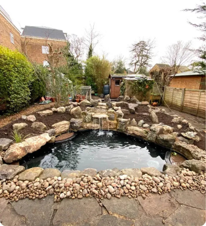 a garden with a pond surrounded by rocks