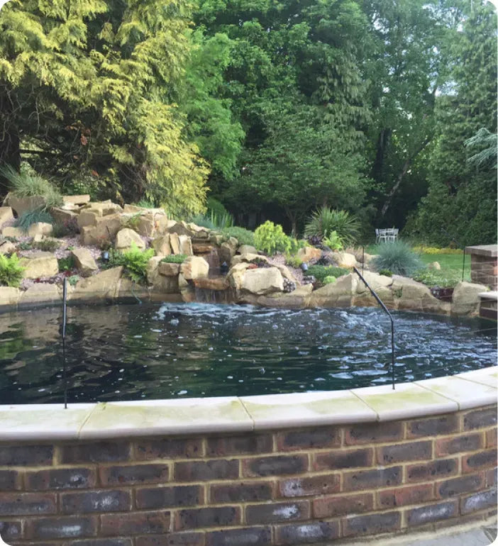 a pool with a waterfall and a rock wall around it