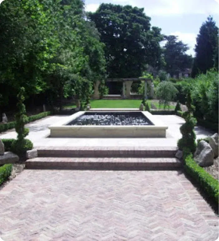 a garden with a fountain surrounded by trees