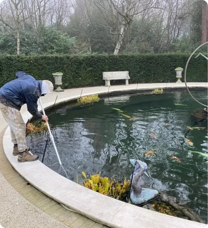 a man is cleaning a pond with a mop