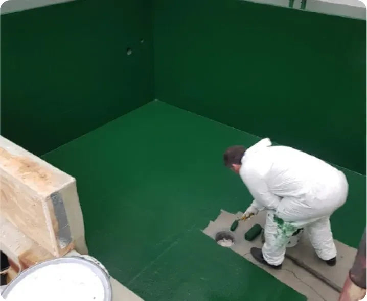 a man in a white suit painting a green wall