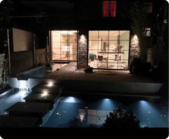 a house lit up at night with a swimming pool