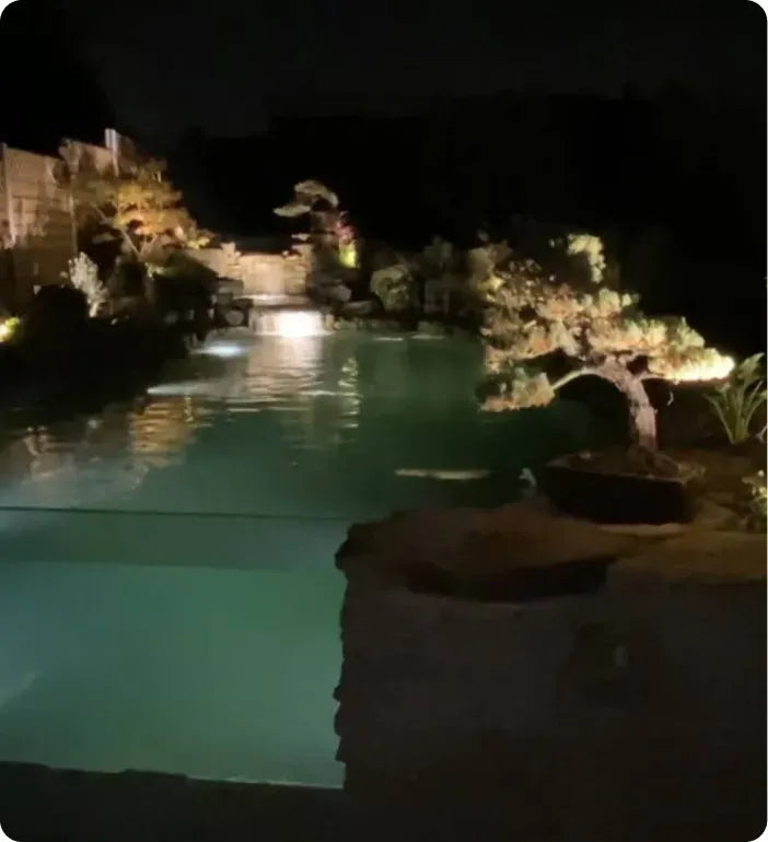 a pool at night with lights on the side of it