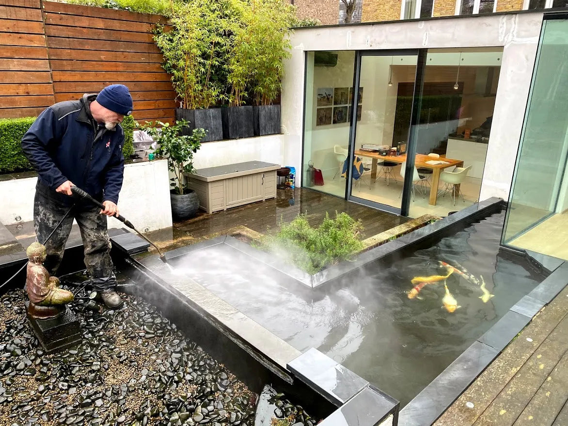 a man using a water hose to clean a pond