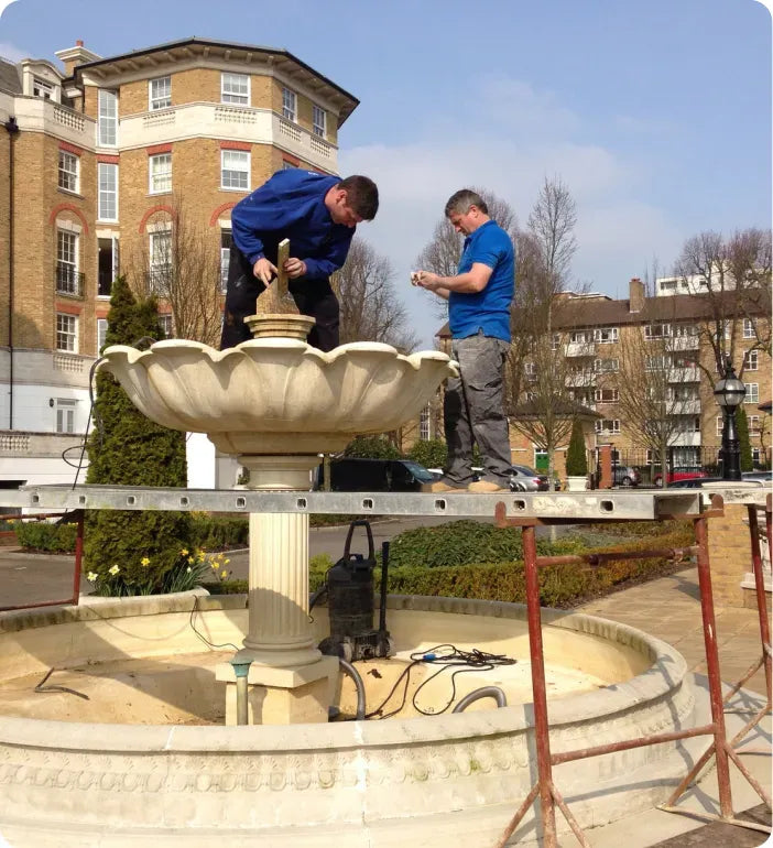 a couple of men standing on top of a fountain