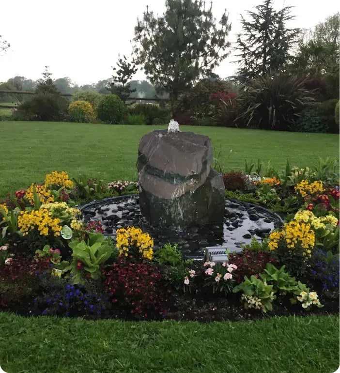 a fountain surrounded by flowers in a garden