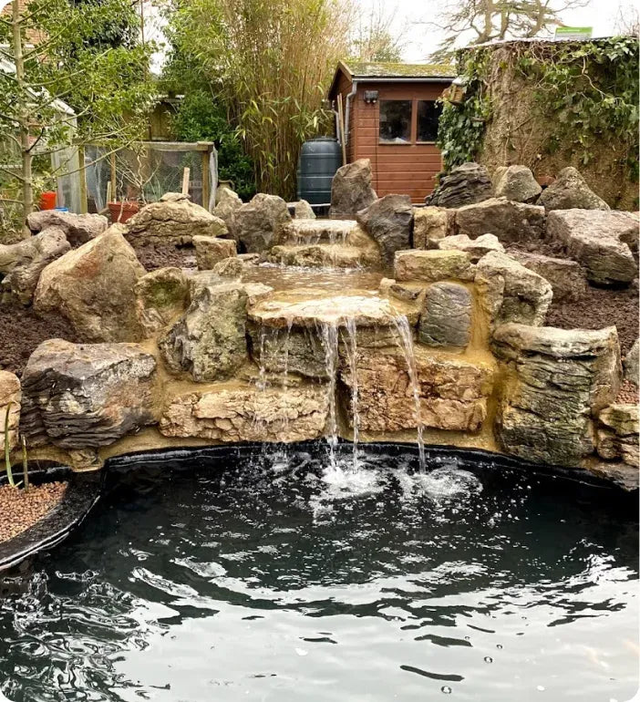 a backyard pond with a waterfall and a rock waterfall