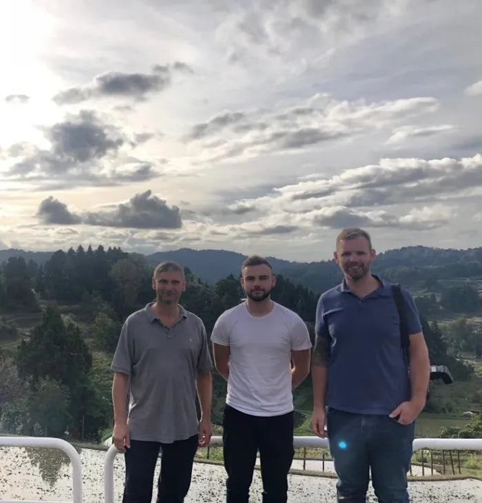 three men standing next to each other in front of a mountain