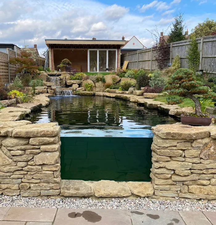 a garden with a pond surrounded by stone walls