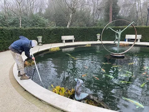 a man is cleaning a pond in a park