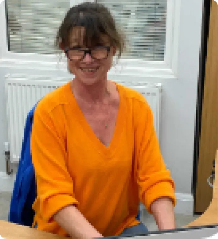 a woman sitting at a desk in front of a laptop computer