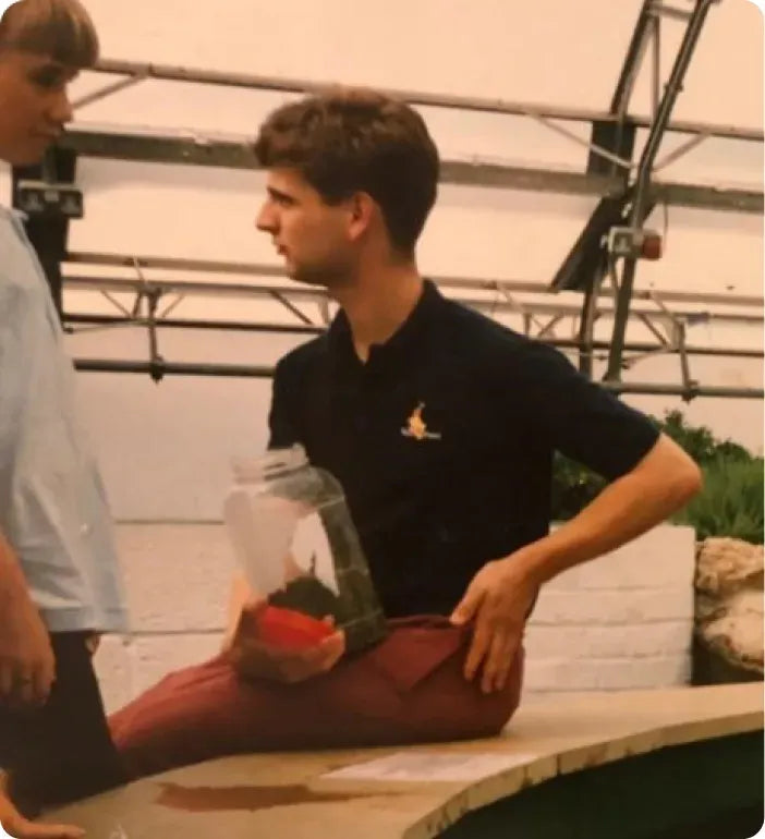 a man sitting on a ledge holding a container of fruit