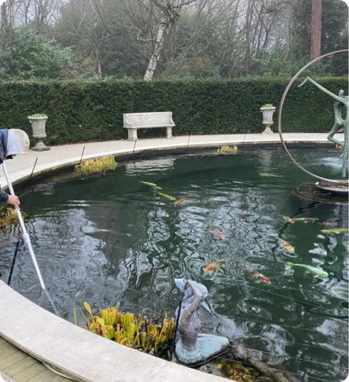 a man is cleaning a pond with a pole