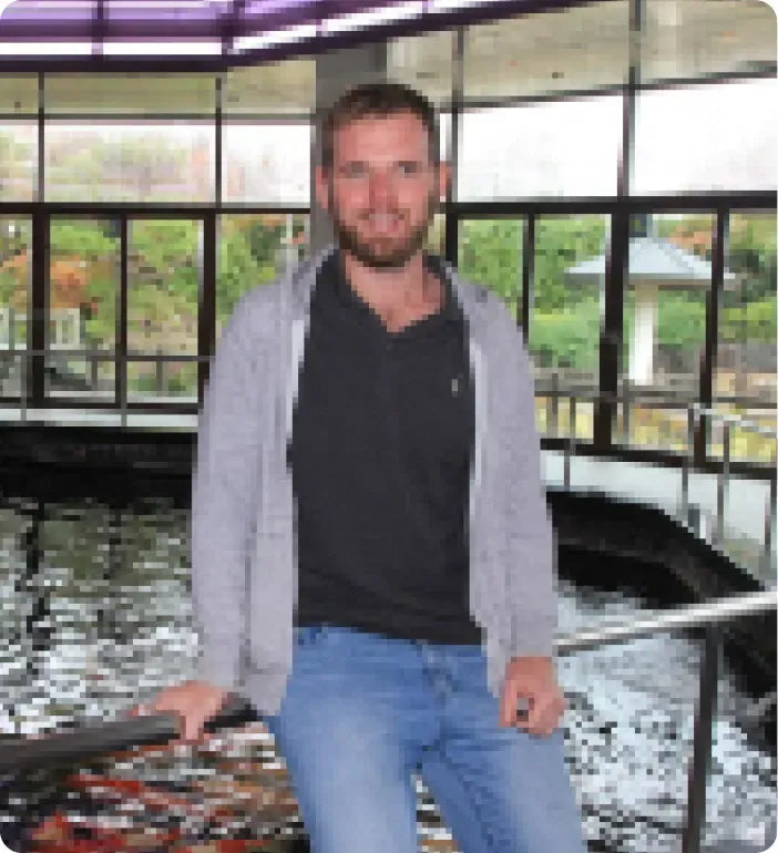 a man sitting on a railing next to a pond